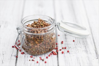 Preserved Pink Peppercorns on an old wooden table as detailed close-up shot, selective focus