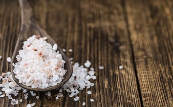 Salt (pink) on an old wooden table as detailed close-up shot (selective focus)