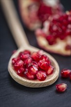 Portion of Pomegranate seeds on a rustic slate slab (selective focus, close-up shot)