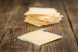 Cheese (sliced) on an old wooden table as detailed close-up shot (selective focus)