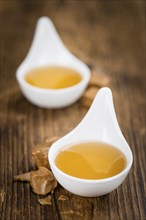 Caramel Syrup as high detailed close-up shot on a vintage wooden table (selective focus)