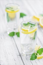 Homemade Lemonade on an wooden table (selective focus) as detailed close-up shot