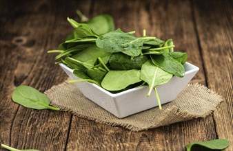 Portion of fresh Spinach on an old wooden table (close-up shot)