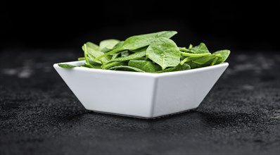 Vintage looking table with fresh Spinach (detailed close-up shot, selective focus)