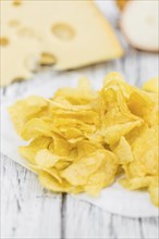 Cheese and Onion Potato Chips on rustic wooden background (close-up shot)