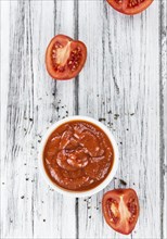 Tomato Ketchup on an old wooden table as detailed close-up shot (selective focus)