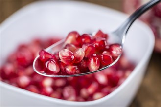 Pomegranate on an old wooden table as detailed close-up shot (selective focus)