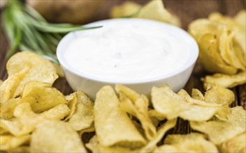 Fresh made Potato Chips with Sour Cream taste on a vintage background (close-up shot)