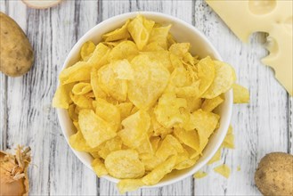 Cheese and Onion Potato Chips on rustic wooden background (close-up shot)