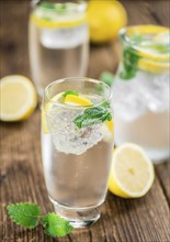 Homemade Lemonade on an wooden table (selective focus) as detailed close-up shot