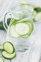 Fresh made Cucumber Water as high detailed close-up shot on a vintage wooden table, selective focus