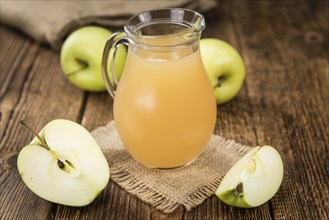 Homemade Apple Juice on an wooden table (selective focus) as detailed close-up shot