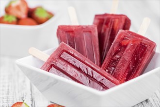 Strawberry Popsicles (close-up shot, selective focus) on a rustic background