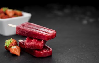 Homemade Strawberry Popsicles (close-up shot, selective focus) on vintage background