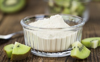 Bowl with fresh made Kiwi powder (close-up shot, selective focus) on an old wooden table