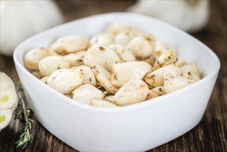 Marinated Garlic on an old wooden table as detailed close-up shot (selective focus)