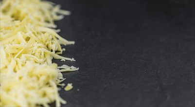 Homemade Grated Cheese (close-up shot) on a vintage slate slab