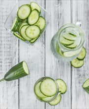 Fresh made Cucumber Water as high detailed close-up shot on a vintage wooden table, selective focus