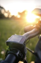 Handlebars of a bicycle in a green meadow at sunset, e-bike, Black Forest, Gechingen, Germany,