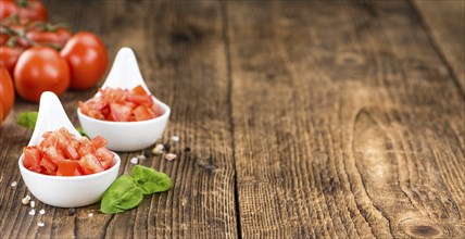 Tomatoes (diced) as high detailed close-up shot on a vintage wooden table (selective focus)