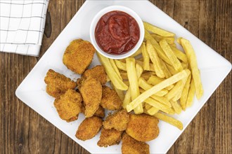 Vintage wooden table with fresh made Chicken Nuggets (close-up shot, selective focus)