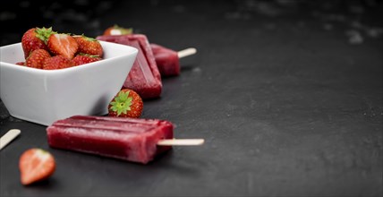 Slate slab with homemade Strawberry Popsicles (selective focus, close-up shot)