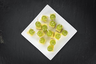 Cheese blocks with grapes as close-up shot on a vintage looking slate slab (selective focus,