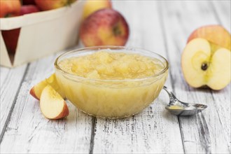 Portion of fresh made Applesauce (selective focus) on a wooden table