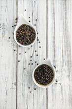 Black Peppercorns preserved on wooden background, selective focus, close-up shot