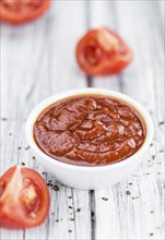 Homemade Tomato Ketchup on an wooden table (selective focus) as detailed close-up shot