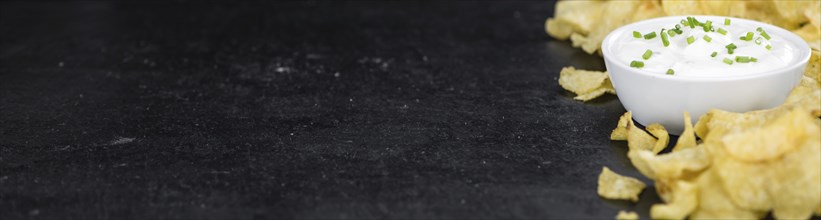 Some Potato Chips with Sour Cream taste on a slate slab (close-up shot, selective focus)