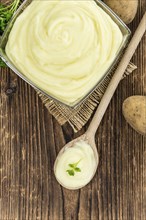 Portion of homemade Mashed Potatoes on wooden background (selective focus, close-up shot)