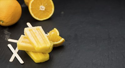 Orange Popsicles (selective focus, close-up shot) on a vintage background