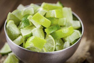 Sliced Limes on rustic wooden background (close-up shot)