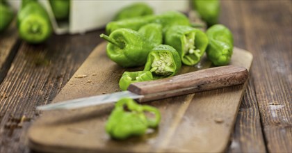 Raw Pimientos on an old wooden table as detailed close-up shot, selective focus