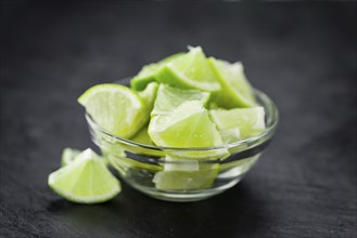 Portion of Sliced Limes as detailed close up shot on a slate slab (selective focus)