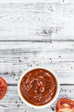 Fresh made Ketchup on a vintage background (close-up shot)