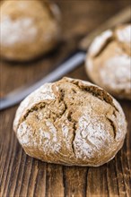 Wholemeal Roll on rustic wooden background (close-up shot)