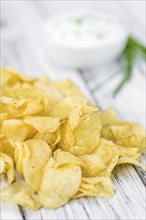 Fresh made Potato Chips with Sour Cream taste on a vintage background (close-up shot)