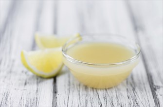 Fresh made Juice (lemon) on an old and rustic wooden table (selective focus, close-up shot)