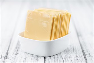 Cheese (sliced) on an old wooden table as detailed close-up shot (selective focus)