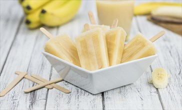 Banana Popsicles (on wooden background) as detailed close-up shot