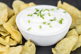 Fresh made Potato Chips with Sour Cream taste on a vintage background (close-up shot)