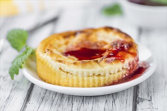 Mini Cheesecake (with Sauce) as high detailed close-up shot on a vintage wooden table (selective