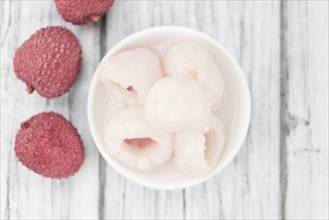 Lychees (preserved) as high detailed close-up shot on a vintage wooden table (selective focus)