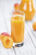 Fresh made Apricot Juice on a vintage background (close-up shot)