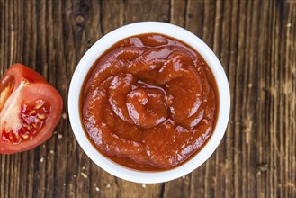 Homemade Tomato Ketchup on an wooden table (selective focus) as detailed close-up shot