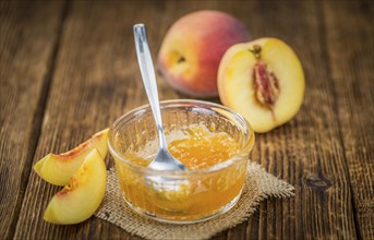 Peach Jam on an old wooden table as detailed close-up shot, selective focus