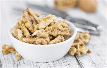 Cracked Walnuts as high detailed close-up shot on a vintage wooden table (selective focus)