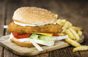 Homemade Fish Burger (close-up shot, selective focus) on a wooden table